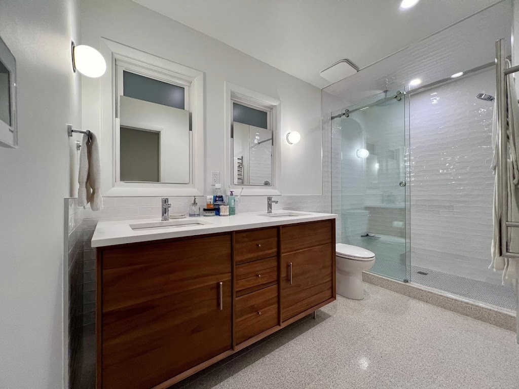 Jack C. Glass Electric — bathroom double vanity with sconce side lighting and overhead pendants, glass shower behind