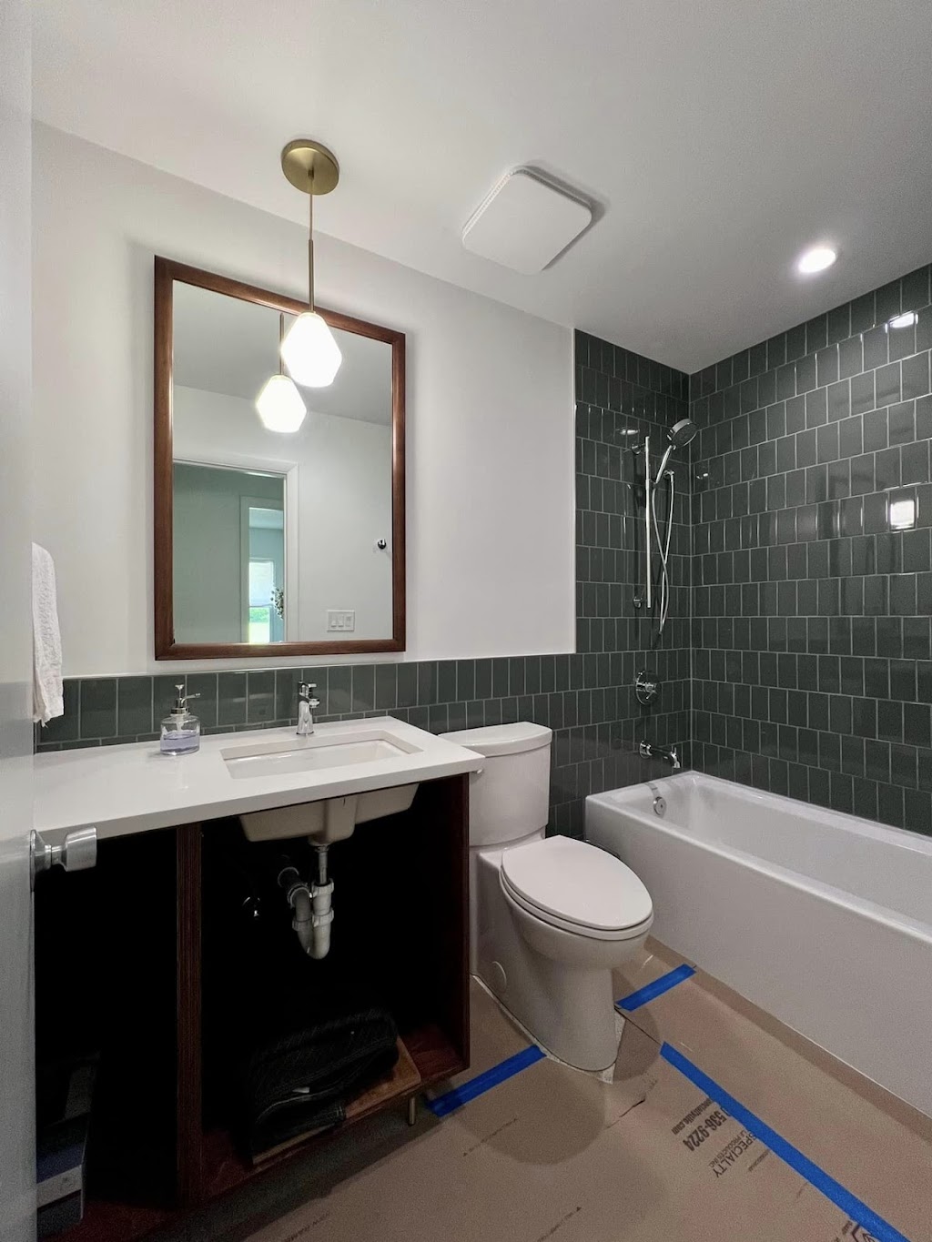 Jack C. Glass Electric — second bathroom with brass pendant mirror light, square overhead exhaust-light combo, and recessed lighting above the tub